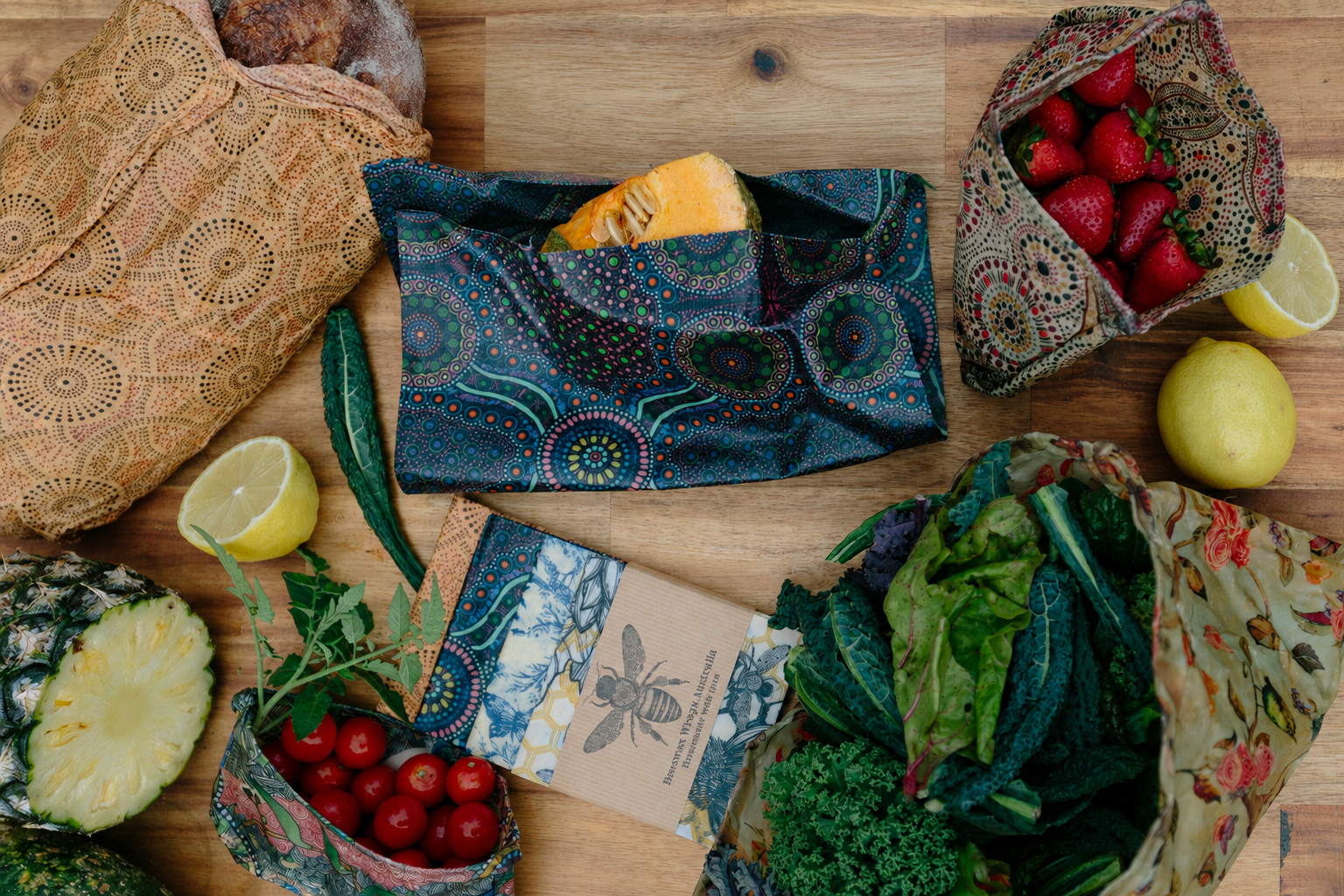 Beeswax wraps covering fruit, vegetables and bread on a wooden table